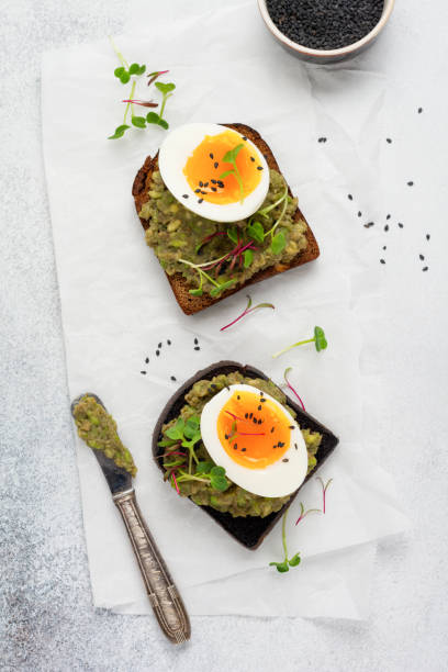 istock Healthy sandwich with avocado, eggs and microgreens on toast on a serving plate for breakfast. Healthy nutrition dietary concept. Top view 1308607454