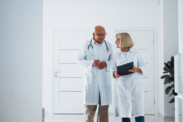 istock Two senior doctors stands in the clinic with notepad and talks to each other 1308608795
