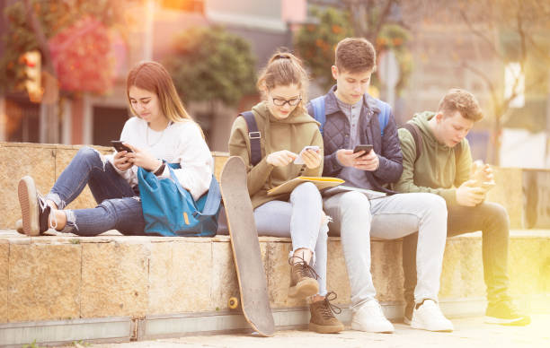 istock Group of teens using smartphones outdoors 1308608971