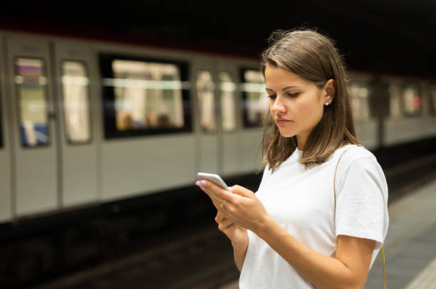 istock Woman waiting subway car using phone 1308609002