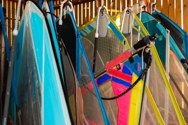 Windsurfing sails storage on a beach watersports facility. Surfer boards on shelf lie  under the roof for rental. Colorful sails background in sunlight