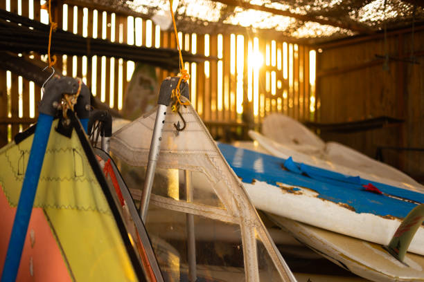istock Windsurfing sails storage on a beach watersports facility. Surfer boards on shelf lie  under the roof for rental. Colorful sails background in sunlight 1308614347