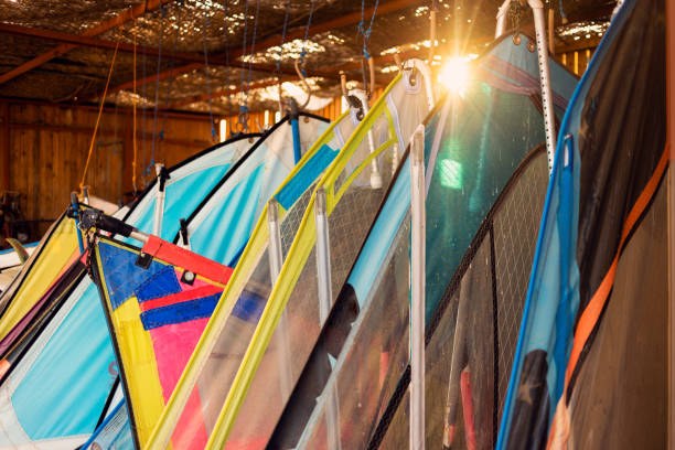 istock Windsurfing sails storage on a beach watersports facility. Surfer boards on shelf lie  under the roof for rental. Colorful sails background in sunlight 1308614358