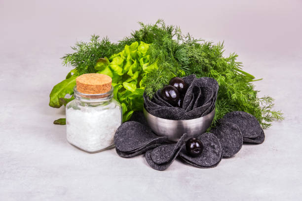 istock Black chips and black olives. Chips with salt and fresh herbs 1308615153