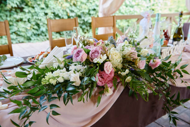 istock Lush floral arrangement on wedding table outdoors. Wedding presidium in restaurant, copy space. Banquet table for newlyweds with pink and purple rose flowers. Luxury wedding decorations 1308617511