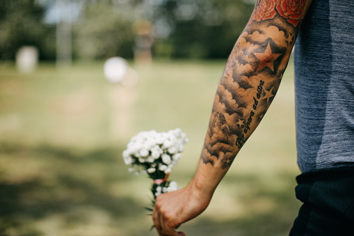 Young tattooed man holding a flower bouquet