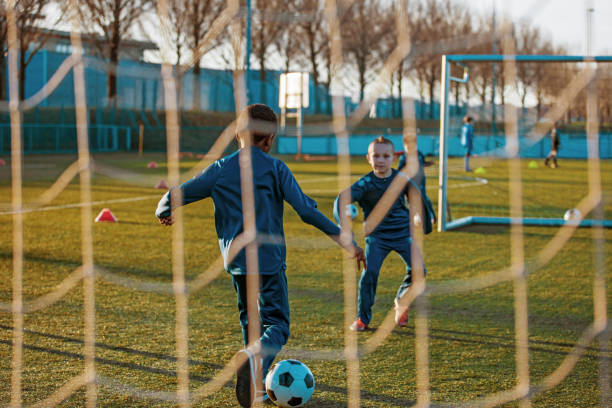 a small group of young boys and their coach training on the football pitch - holanda futebol imagens e fotografias de stock