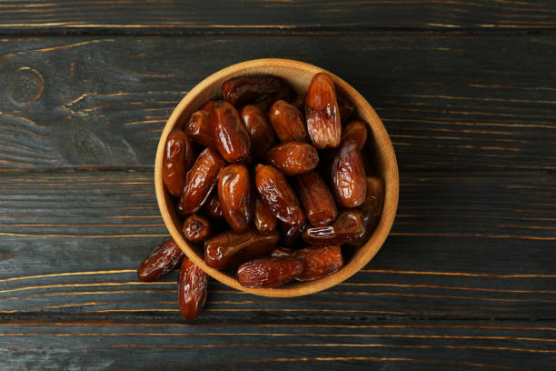 istock Bowl with dried dates on wooden table 1308619037