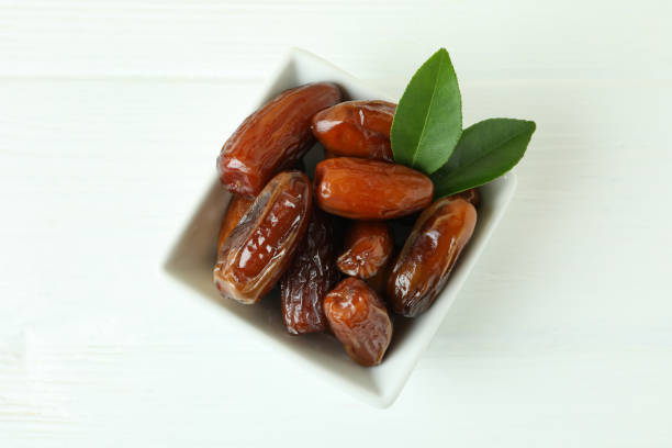 istock Bowl with dried dates on white wooden table 1308619374
