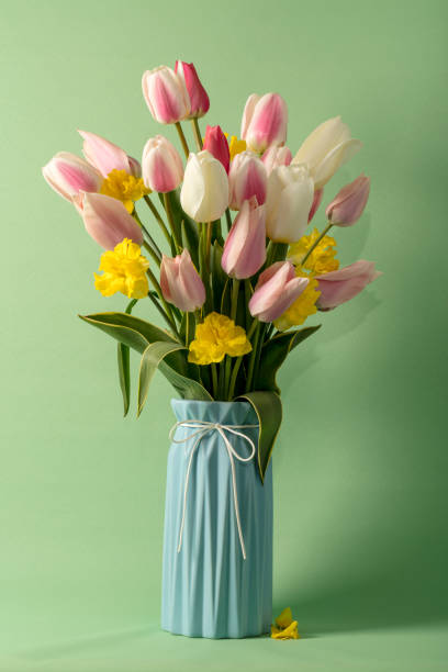 bouquet of flowers (tulips and daffodils) in a vase on a green background - tulip vase flower spring imagens e fotografias de stock