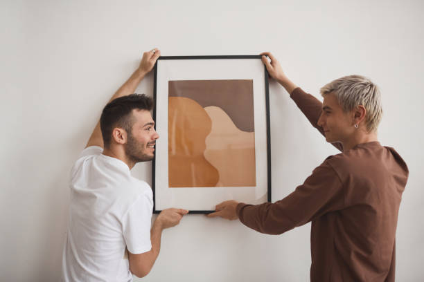 istock Two Young Men Hanging Picture on Wall 1308621367