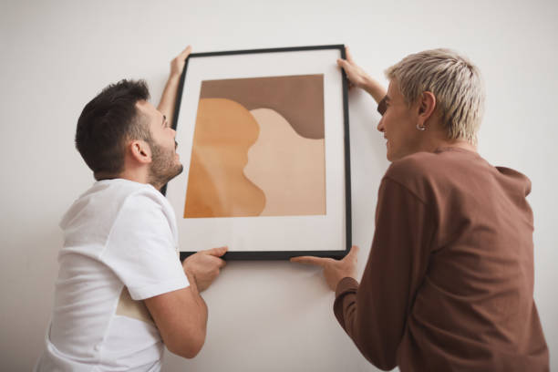 istock Young Men Hanging Picture on Wall 1308621372
