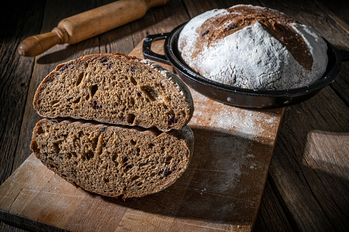 Sourdough bread loaf homemade with cast iron pan showing inner texture crumb detail on rustic wood table background with black olives