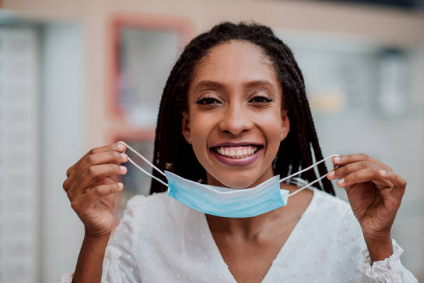 istock Woman smiling and removing face protection mask 1308622838