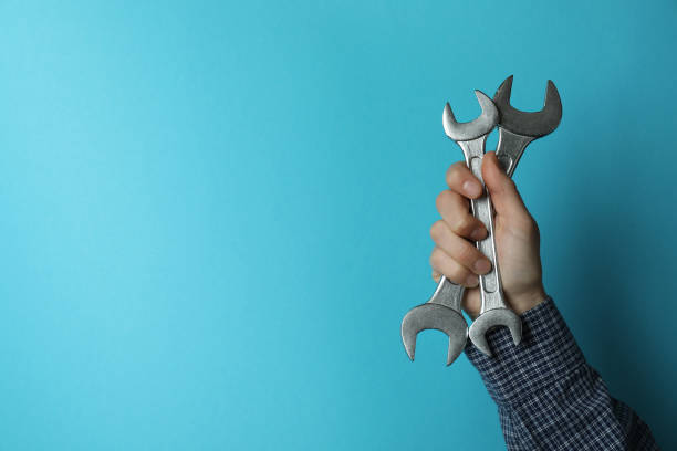istock Male hand holds wrenches on blue background 1308624745