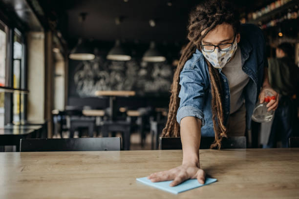 istock Waiter with protective face mask disinfecting tables in a pub 1308624835