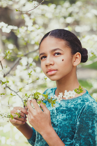 Beautiful girl with a ladybug oh her face surrounded by blooming trees in springtime