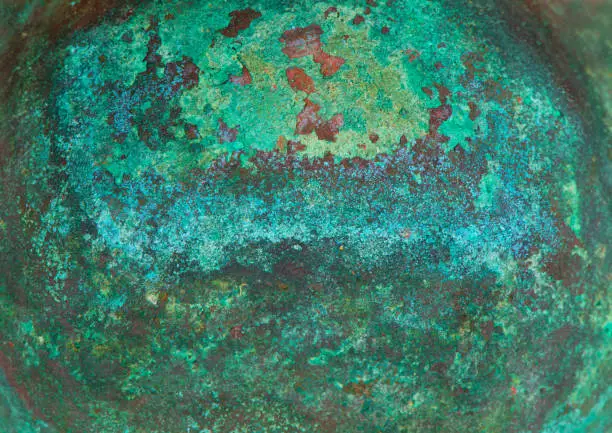 Photo of Aged copper plate texture with green patina stains. Old worn metal background