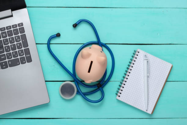 Laptop with piggy bank, stethoscope, notebook on a blue background. Online doctor. Top view. Flat lay Laptop with piggy bank, stethoscope, notebook on a blue background. Online doctor. Top view. Flat lay operating budget stock pictures, royalty-free photos & images