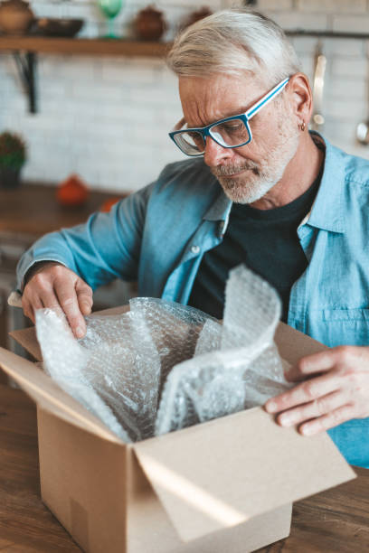 istock Open the parcel. A senior man unpacks a delivery. Goods by mail 1308629928