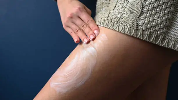 Woman smears cream on her leg with her hands, close-up . High quality photo