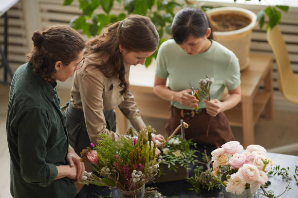 группа людей, создающих цветочные композиции в мастерской - florist flower arranging male стоковые фото и изображения