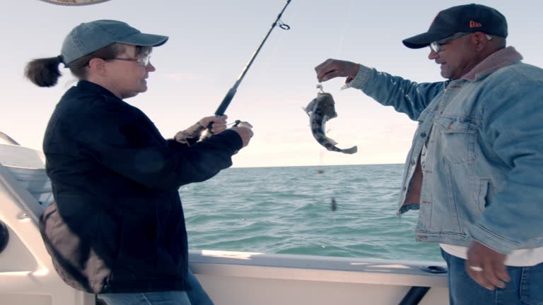 Boat Captain Of A Fishing Charter Boat Holds Up The Small Sea Bass That A Middle-Aged Woman Just Caught Off The Reef In The Sea Of Cortez, Mexico, Puerto Penasco, Video