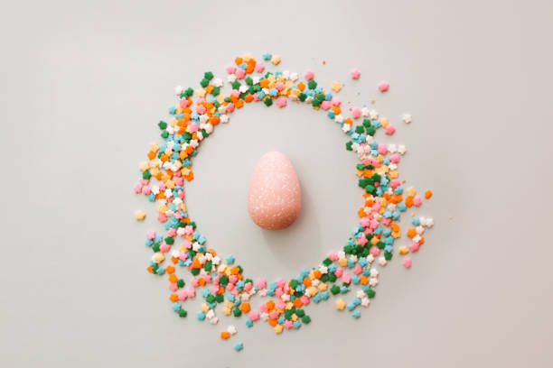 istock Pink Easter egg on light blue background with holiday sprinkles. Easter holiday background. 1308637143