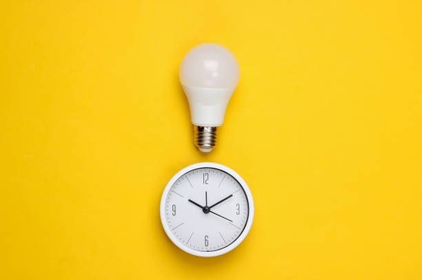istock Clock with light bulb on a yellow background. I have an idea! Minimalism. Top view 1308637146