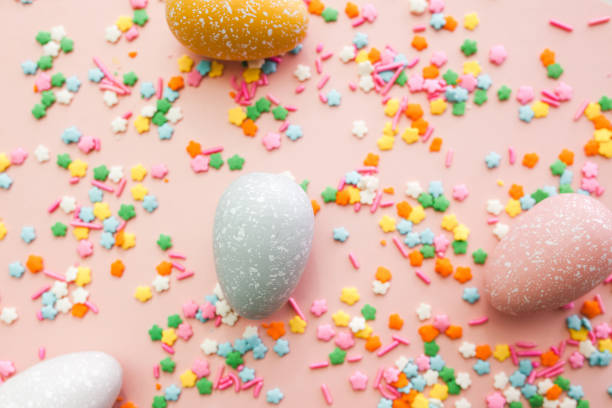 istock White, grey and yellow eggs on pink background with colourful sprinkles. Easter holiday background. 1308637326
