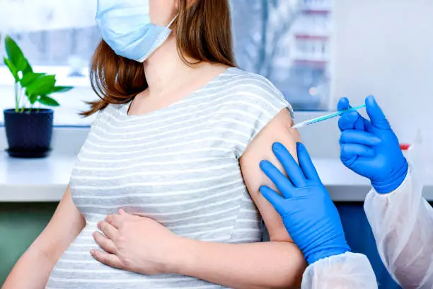 Photo of Pregnant Vaccination. Pregnant Woman In Face Mask Getting Vaccinated in Clinic. Doctor Giving Corona Virus Vaccine Injection Patient. Covid-19 Flu Protection. Selective focus.