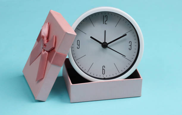 Clock in a gift box on blue background. stock photo
