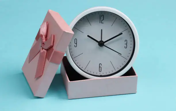Photo of Clock in a gift box on blue background.