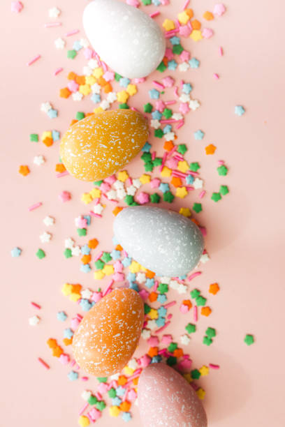 istock White, grey and yellow eggs on pink background with colourful sprinkles. Easter holiday background. 1308637568
