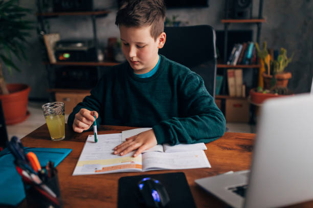 istock Smart 9 year old boy, doing a research for his homework, preparing the material for th tomorrow online class with a tutor 1308637854