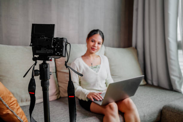 istock Asian blogger, podcaster or vlogger looking at camera and talking on video shooting with technology. Social media influencer people or content maker concept in relax casual style at home 1308637925