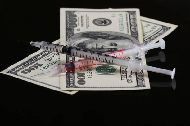 istock Syringes with hundred dollar bills on a black background 1308641138