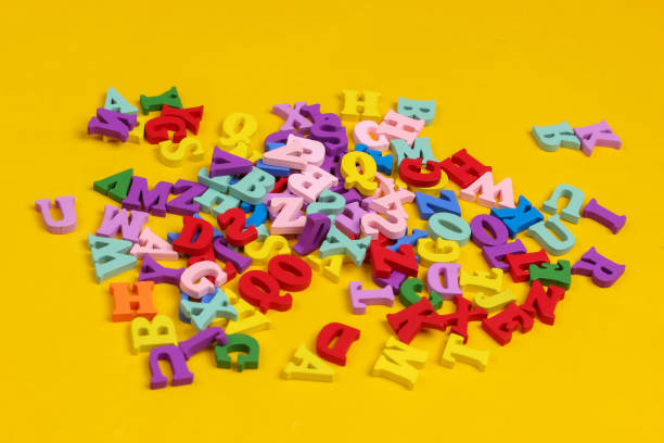 istock Many colored wooden letters isolated on yellow background. 1308641396