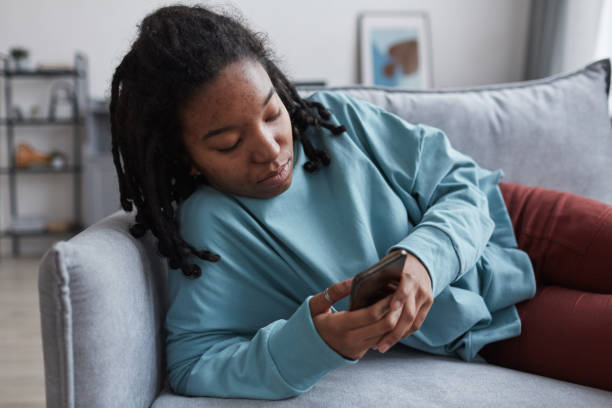 istock Real African American Woman Texting on Couch 1308641661
