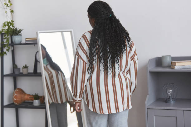overweight african american woman looking in mirror back view - women body beauty candid imagens e fotografias de stock