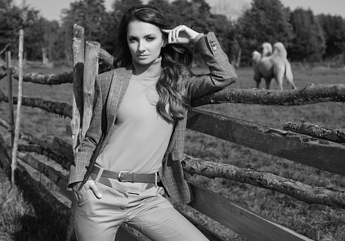 Portrait of a gorgeous brunette woman in an elegant checkered brown jacket posing on country landscape