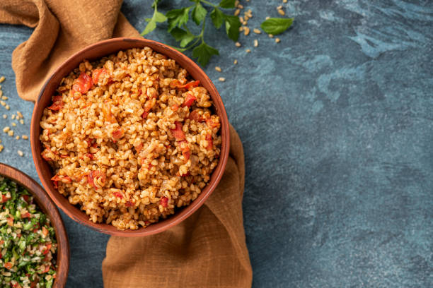 Easy bulgur pilaf (pilavi) with tomatoes Easy bulgur pilaf (pilavi) with tomatoes in a ceramic bowl on a dark background top view. Turkish cuisine, vegan food. pilau rice stock pictures, royalty-free photos & images