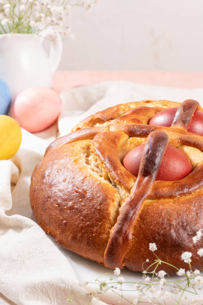 istock Portuguese traditional Easter cake. Folar with eggs on easter table. Blossom flowers and colorful painted eggs 1308651855