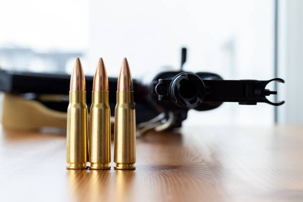 istock Three bullets against blurred Kalashnikov assault rifle background. Cartridges 7.62 caliber for ak 47 closeup 1308652020
