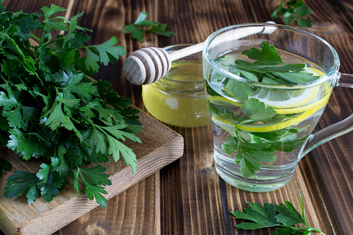 Tea with parsley,honey and lemon in the glass cup on the wooden background. Close-up.