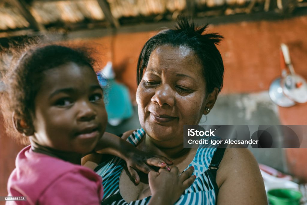 Grandmother with granddaughter on her lap Grandfather and black granddaughter on lap inside home Poverty Stock Photo