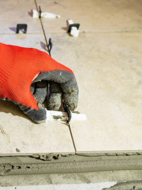 istock Workers are using plastic clamps and wedges to leveling the ceramic tile on the floor. Tile leveling system. 1308656595