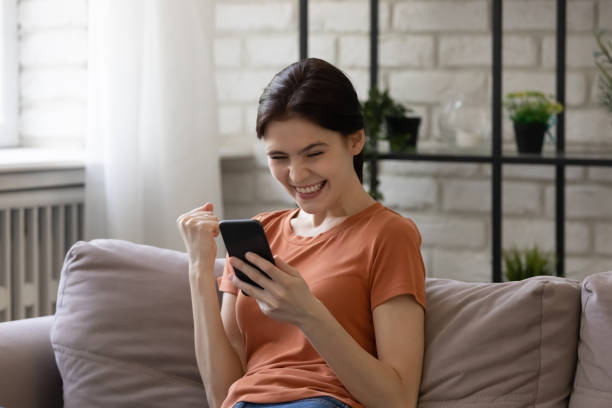 istock Overjoyed young woman looking at phone screen, celebrating success 1308658881