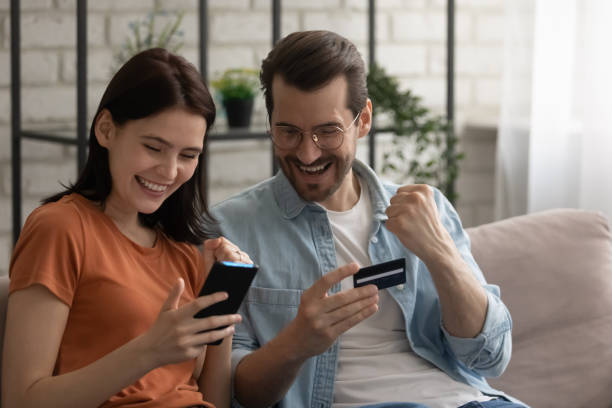 istock Overjoyed young couple checking credit card balance, using smartphone 1308658928