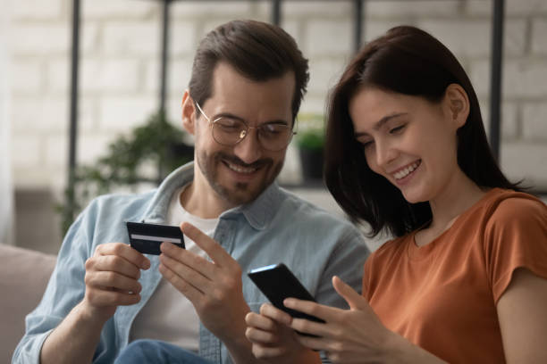 istock Close up happy young couple paying online, using smartphone 1308658934